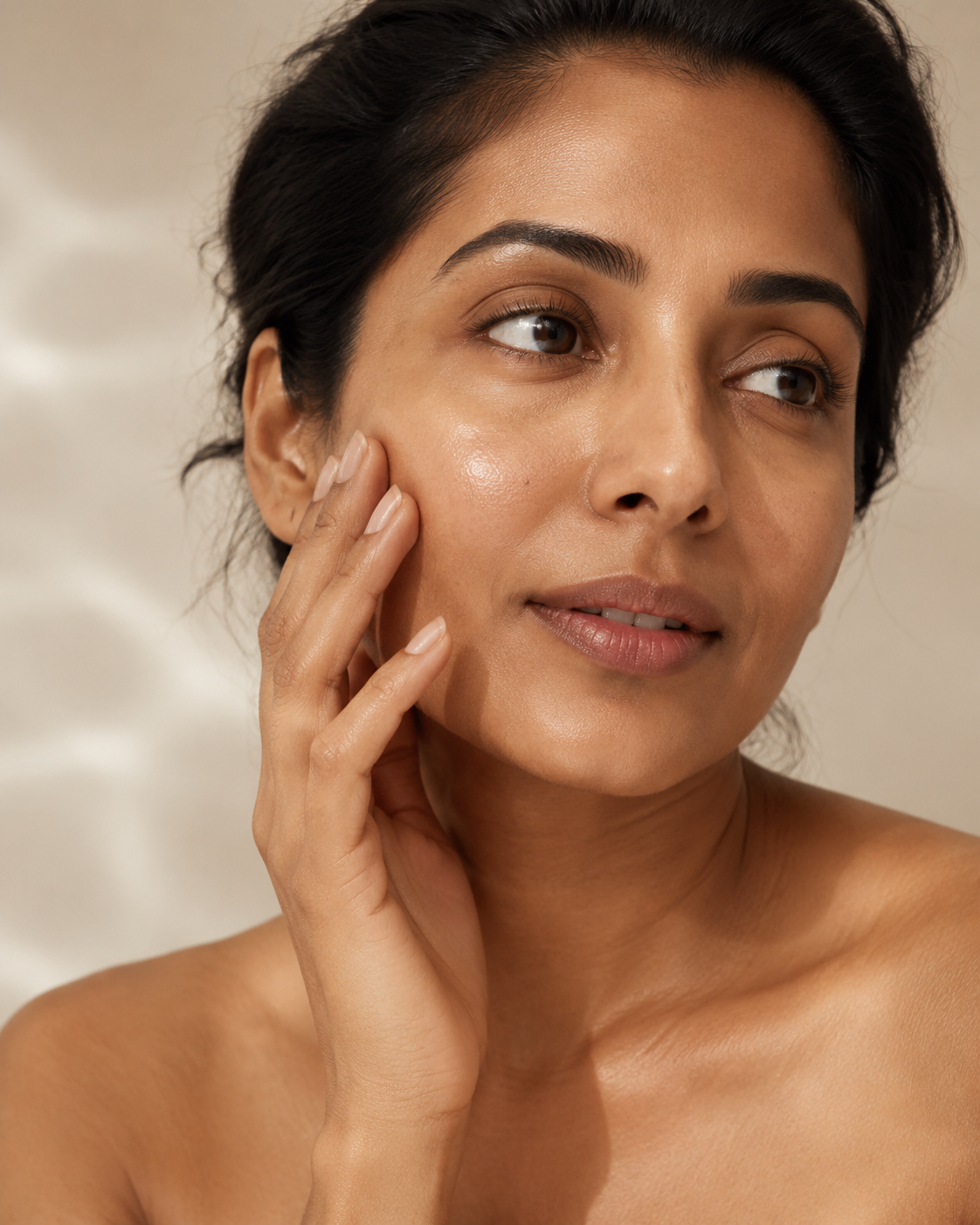 Woman touching hydrated-looking skin in soft light for skin barrier support